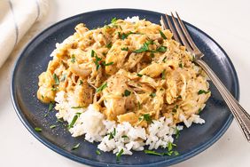 Slow Cooker Chicken and Gravy garnished with fresh herbs and served over white rice on a plate with a fork 