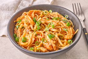 Slow Cooker Asian Zing Chicken Noodles garnished with green onions and sesame seeds in a bowl 