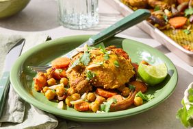 A plate Sheet Pan Chicken and Chickpeas, served with a lime wedge and herbs, with a baking sheet in the background 