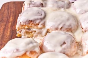 A batch of Ooey Gooey Hawaiian Roll Cinnamon Rolls with icing on a wooden tray