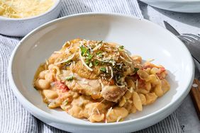 Chicken dish served on a plate with beans and garnished with cheese and herbs