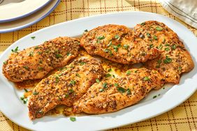 A plate of garlic butter chicken cutlets garnished with herbs served on a table