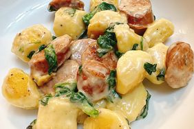 white plate with gnocchi, sausage, and spinach