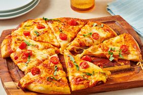 Sliced pan pizza with cheese cherry tomatoes and basil on a wooden board