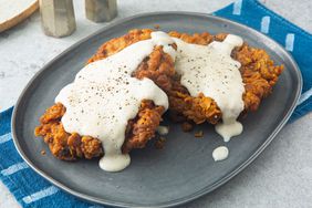 Close up on a plate of the best chicken fried steak, topped with gravy.