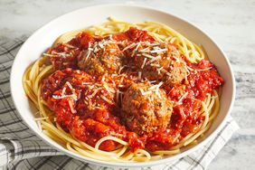 a low angle view looking into a single serving of spaghetti topped with a red sauce, meatballs, and parmesan cheese.
