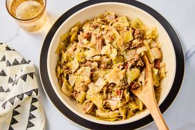 A large bowl of ground beef and cabbage with a wooden serving spoon, served with a glass of sparkling water