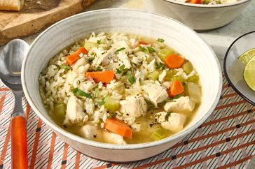 Bowl of chicken and rice soup garnished with herbs