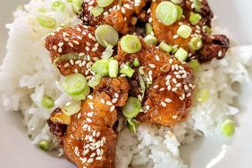 orange chicken over rice topped with green onions and sesame seeds