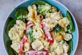 a top down view of a colorful tortellini salad served over spinach greens