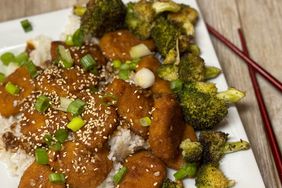 overhead view of chicken nuggets with broccoli over rice with chopsticks