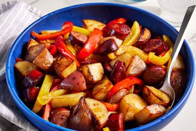 Kielbasa with peppers and potatoes served in a blue bowl. 
