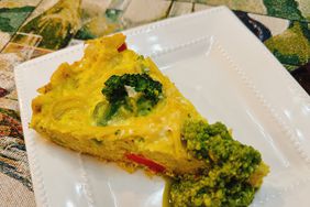 wedge of frittata with pesto on white plate