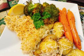 White square plate with parmesan-crusted fish, potatoes, carrots, and broccoli