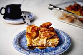 square slice of chicken and waffles casserole on blue willow plate with syrup pitcher in background