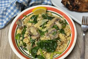 closeup of bowl of mushroom spinach rotini on wooden table
