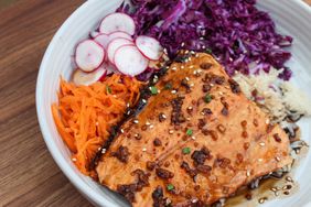 white bowl with rice, radish, carrot, red cabbage, and salmon filet