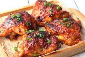 4 beautifully caramelized chicken thighs on a parchment lined bamboo tray