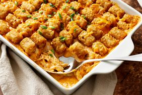 Buffalo Chicken Tater Tot Casserole garnished with green onions in a baking dish with serving spoon