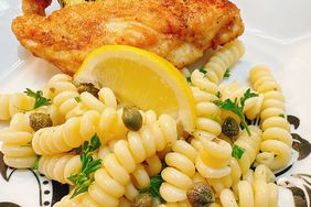 closeup of rotini pasta with lemon and capers plated with chicken