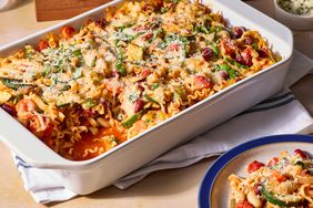 Minestrone casserole served in a white baking dish on a table next to a plate with casserole 