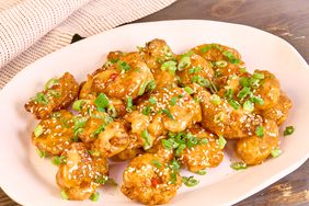 pale pink platter of fried bang bang chicken nuggets with sliced green onions