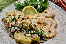 white plate with shrimp, rice, and vegetables garnished with lemon and parsley