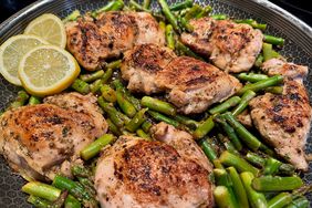 skillet with browned chicken thighs and asparagus in lemon sauce