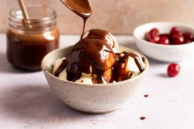 Chocolate sauce being drizzled over vanilla ice cream.