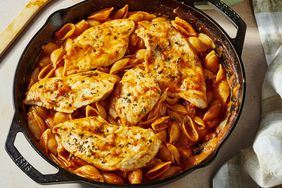 A cast iron skillet with one pot chicken Pomodoro, with a bowl of chicken Pomodoro in the background