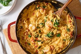 Creamy shrimp orzo pasta with spinach and tomatoes in skillet.
