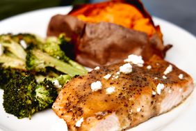 plated roasted broccoli and salmon with baked sweet potato in background