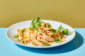 Chilled Lo Mein Noodles with Szechuan Peppercorns garnished with cilantro on a plate on top of a blue surface