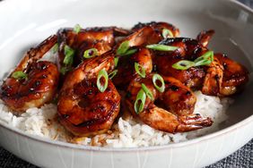 a bowl of honey-garlic shrimp garnished with green onions served over rice