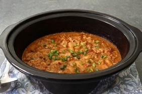 Chicken chili topped with green onions in a slow cooker