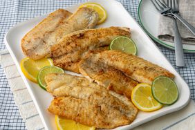 high angle looking at a plate of pan seared tilapia garnished with lemon and lime slices
