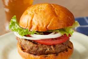 close up view of a perfect basic burger with lettuce, tomato and onions, on a plate