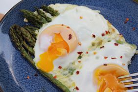 overhead view of blue platter with asparagus spears and two eggs