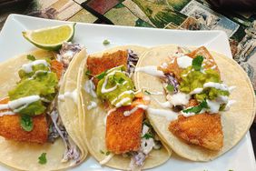 3 fried trout tacos with guacamole and slaw on white square plate