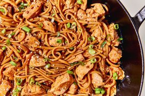 spicy soy noodles with chicken pieces, sesame seeds and scallions in skillet