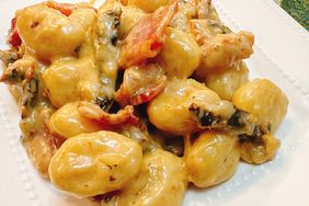 gnocchi with creamy sauce, bacon and sun-dried tomatoes on white plate