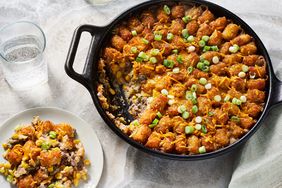 Looking down at a skillet of tater tot hot dish, with a serving on a plate
