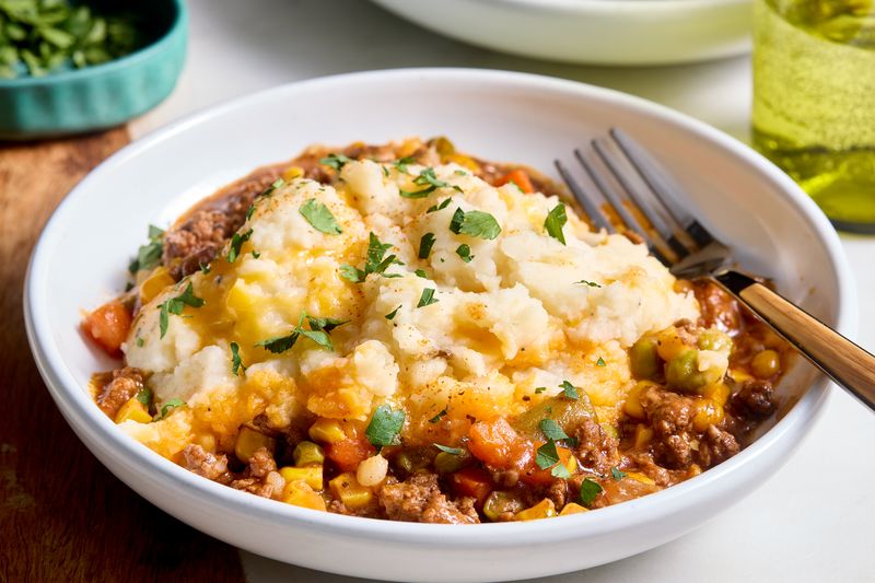 Plated shepherd’s pie garnished with parsley, served with a fork