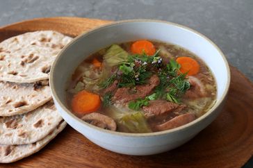 bowl of pork, mushroom, and vegetable Viking stew with herbs and flatbread