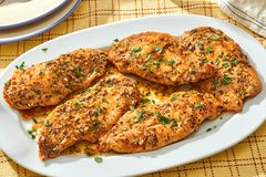 A plate of garlic butter chicken cutlets garnished with herbs served on a table
