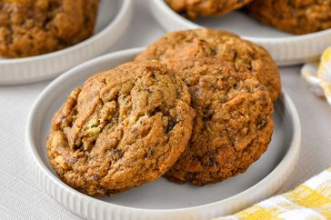 nicely browned banana cookies on several white plates with yellow check napkin