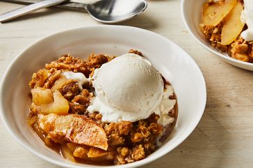 a serving of Apple Crisp in a bowl topped with a scoop of vanilla ice cream