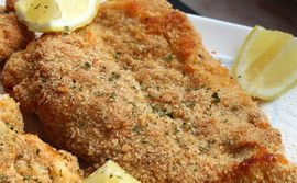 closeup of Baked Chicken Schnitzel garnished with lemon wedges and finely chopped parsley
