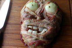 a face-shaped meatloaf with bacon "skin", onion half "eyes" and chopped onion "teeth" for Halloween