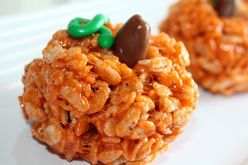 closeup of a Marshmallow Rice Krispies Treat colored orange and shaped like a pumpkin with a Tootsie Roll "stem" and frosting vines